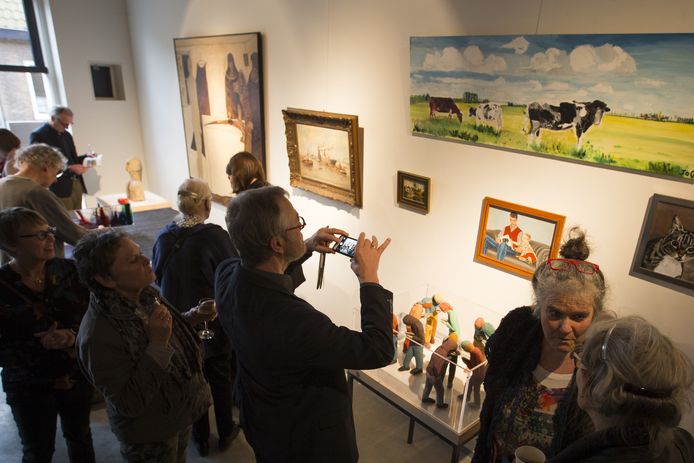 Bezoekers tussen door particulieren uit hun huiskamer ingeleverde schilderijen  en andere kunst die ze voor de duur van de expositie met anderen willen delen.