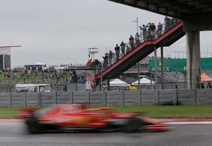 Fans zien in de regen Ferrari-coureur Sebastian Vettel voorbij flitsen.
