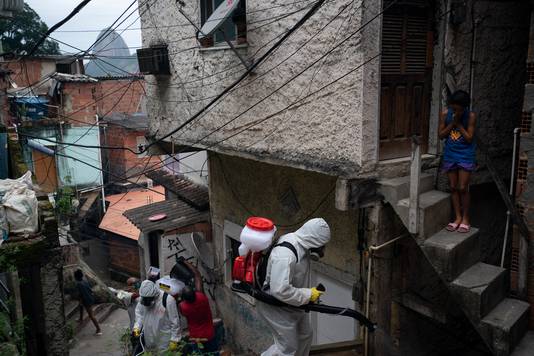 Vrijwillgers spuiten ontsmettingsmiddel in een sloppenwijk in Rio de Janeiro om de verspreiding van het virus tegen te gaan.