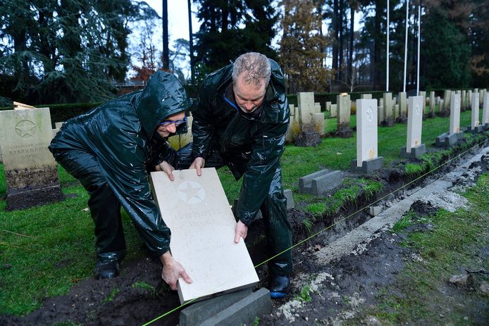 Nico (l) en Bas van de Oorlogsgravenstichting plaatsen een nieuwe grafsteen op het Russisch Ereveld op Rusthof.