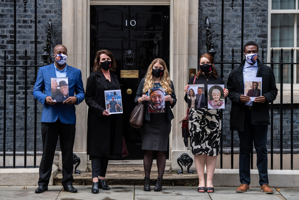 Demonstranten voor de ambtswoning van Boris Johnson houden foto's omhoog van familieleden die zijn overleden aan de gevolgen van Covid-19. Beeld Getty Images