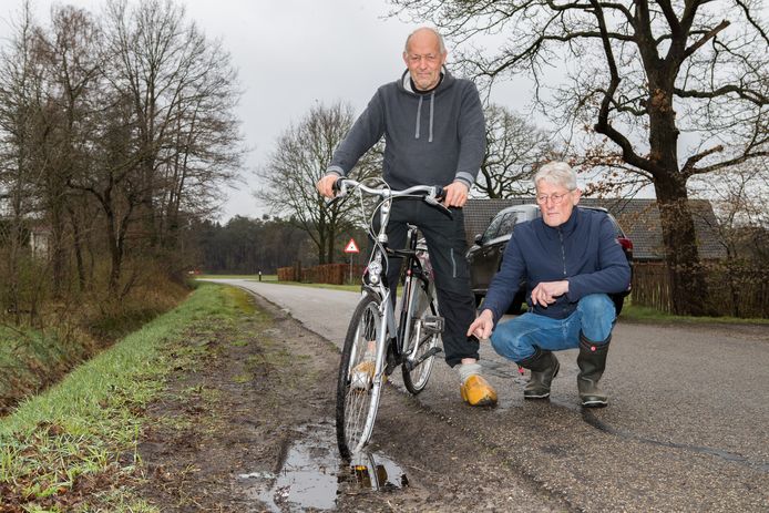 Gerbert Warmelink staat met het voorwiel van zijn fiets in een van de vele knipgaten langs de Oude Hammerweg in Giethmen. Ook buurman Gerard Hermsen vindt dat de slechte bermen snel moeten worden aangepakt.