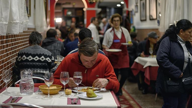 Angel Castillo (51) geniet van zijn gratis maaltijd in Robin Hood, een typisch Spaans restaurant voor arme Madrilenen. Beeld Samuel Aranda