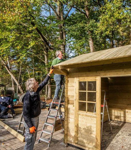 Vrijwilligers bouwen kapschuur in Kloostertuin Zenderen, tussen bloeiende bomen en bloemen