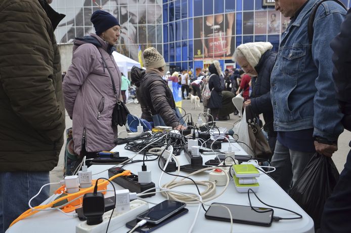 Oekraïners in Cherson laden hun telefoons op met behulp van een generator.