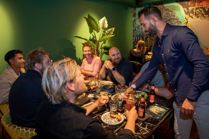 Eigenaar Enes Gulen serveert een gerecht uit aan een tafel.