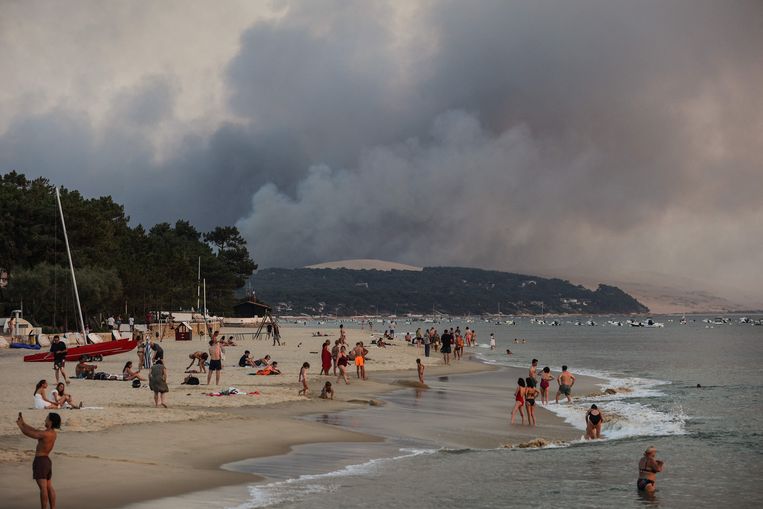 Vlak bij Bordeaux zonnen mensen aan de kust terwijl in de verte bosbranden te zien zijn. Later werden 8.000 inwoners van het gebied geëvacueerd. Beeld AFP