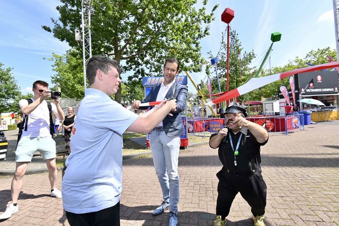 Wethouder Thijs van Kessel krijgt hulp van Jeffrey de Bie en Milko Renz (rechts) bij het officieel openen van de Osse kermis op de Rusheuvel.