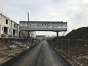 Een foto van de huidige situatie rond de loopbrug op Strijp-R in Eindhoven, met links de andere nieuwbouw in aanbouw. Rechts komt het Bruggebouw te staan.