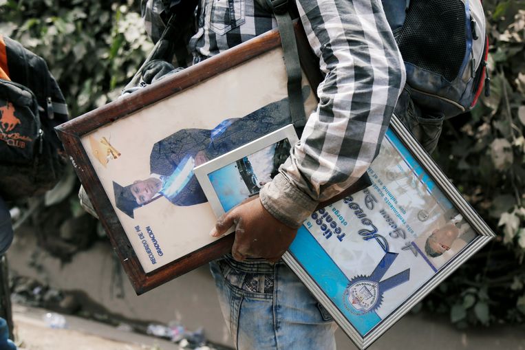 Een man redt enkele persoonlijke spullen – diploma's en foto's – in San Miguel Los Lotes in Escuintla, Guatemala, een gebied dat getroffen werd door de uitbarsting. Beeld REUTERS