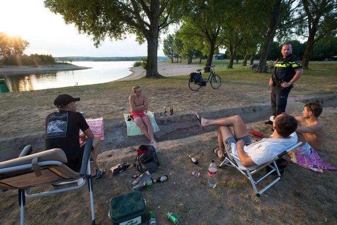 Wijkagent Florus Noppen (rechts) in gesprek met jongeren op het strandje. Een biertje drinken is prima, maar niet na zonsondergang.