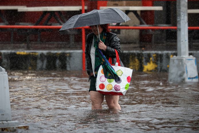 Een vrouw loopt door het kniediepe water in Brooklyn, New York.