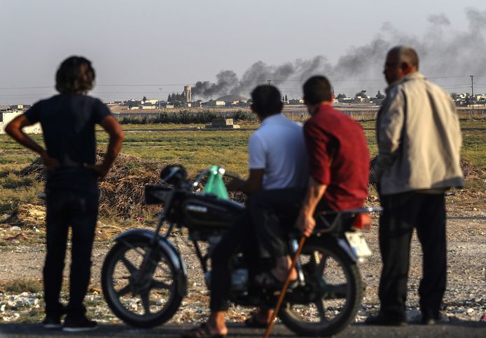 Mensen kijken bij de Turks-Syrische grens naar de rookpluimen die het resultaat zijn van het oorlogsgeweld.