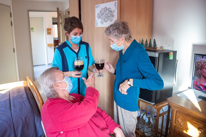 Fien brengt Jeanne (87) en Marie (93) wat plezier in een glas. 't Is op het randje, maar er zit net 1,5 meter tussen hun stoelen én ze dragen hun mondmasker.