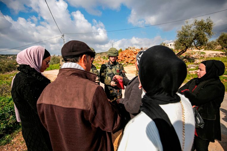 Palestijnen spreken met Israëlische militairen aan een checkpoint in Bruqin, in bezet gebied. Beeld AFP