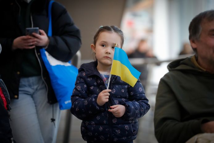 Oekraïens meisje zwaait met vlagje wanneer ze aankomt in Brussel na een tijd in Duitsland te hebben doorgebracht.