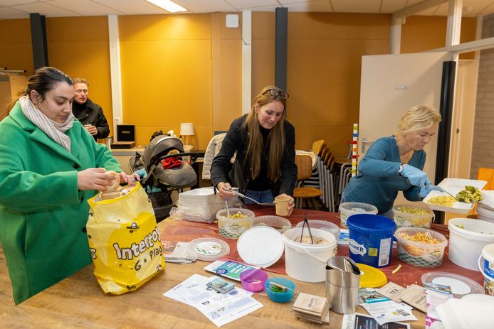 Angelique de Rouw en Ineke (r) geven een bezoeker een tas vol met maaltijden mee.