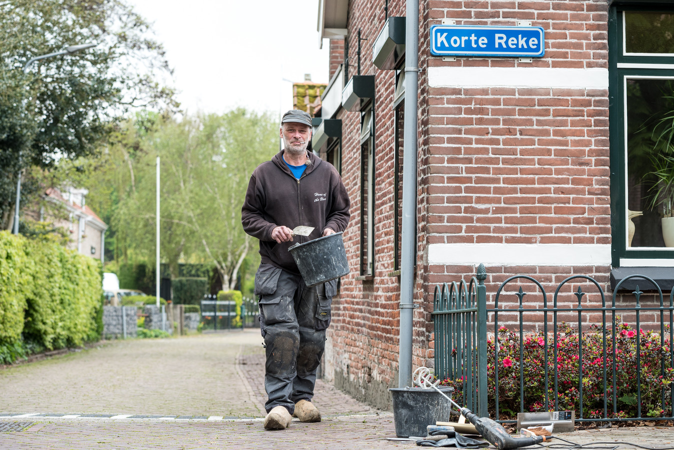 Hans Blom is specie aan het aanbrengen aan de onderkant van een woning op de hoek van de Korte Reke en de Wilhelminaweg in Renesse.