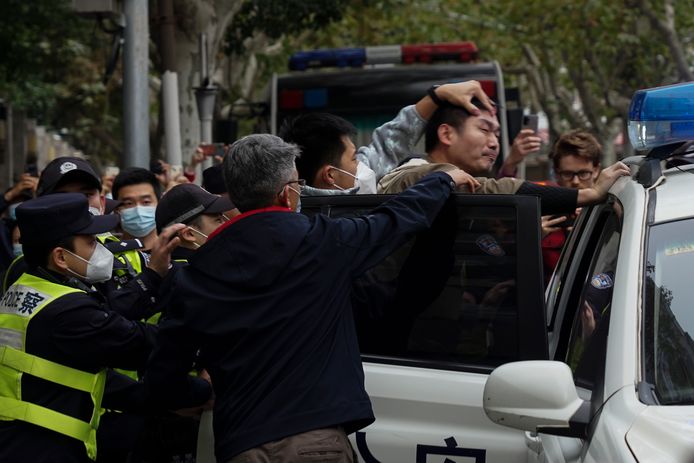 Een demonstrant wordt tijdens een straatprotest in Shanghai hardhandig in een politiewagen geduwd.