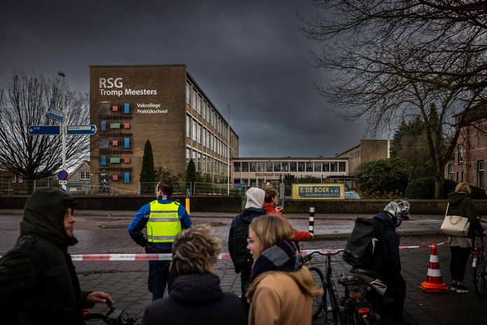 Enkele voorbijgangers bekijken vanachter de linten naar RSG Tromp Meesters, waarvan de gevel aan de rechterkant enkele centimeters is losgekomen. Een handhaver houdt in de gaten dat mensen niet de kruising op komen. ,,Meneer, daar hangt een lint, hè!”