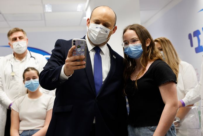 De Israëlische premier Naftali Bennett (midden) poseert met een meisje voor een videoboodschap bij een organisatie die coronavaccins ter beschikking stelt in de Israëlische stad Holon.