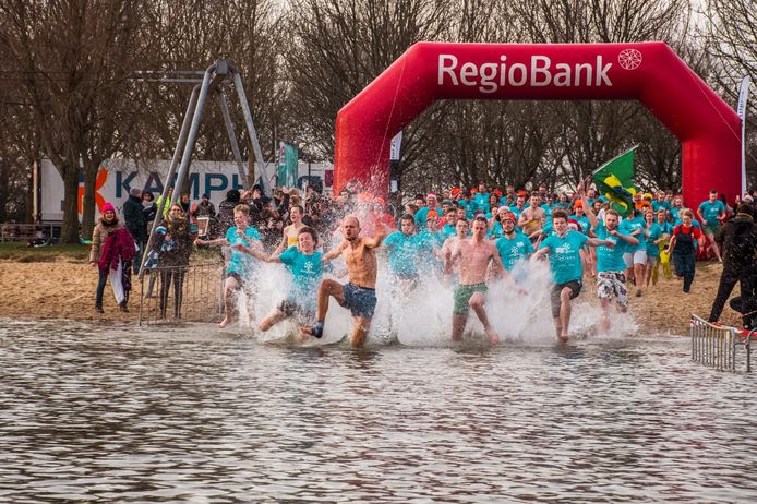 Deelnemers aan de Oudjaarsduik van 2019 rennen het ijskoude water in.