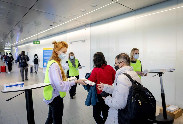 Reizigers uit China krijgen een zelftestkit bij aankomst op Schiphol. Beeld AFP