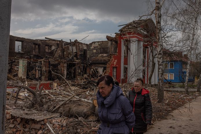 Mensen lopen voor een door de Russen vernietigde school langs in Charkiv. De foto is van gisteren, 14 april.