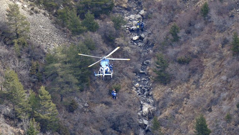 Een helikopter en reddingswerkers nabij de plek waar het toestel van Germanwings is neergestort. Beeld afp