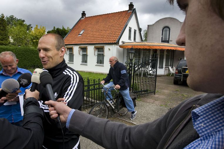 Arjen Robben staat de pers te woord terwijl fysiotherapeut Dick van Toorn op zijn fiets de journalisten ontwijkt. (ANP) Beeld 