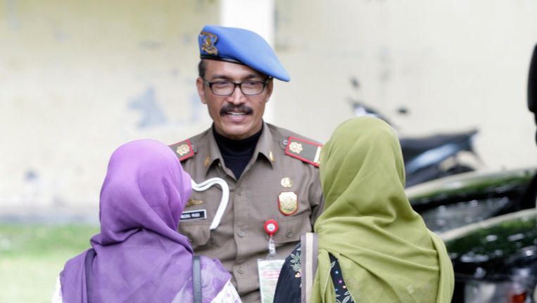 Een agent van de sharia-eenheid praat met twee vrouwen die gearresteerd waren voor het dragen van (te) strakke spijkerbroeken. Beeld EPA