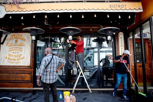 Werknemers van een Parijse bistro maken het terras schoon. Vanaf 2 juni kunnen in het grootste deel van Frankrijk de restaurants, cafés en hun terrassen weer open.