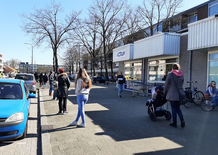 Klanten wachten keurig op hun beurt om de koopjeswinkel binnen te gaan.