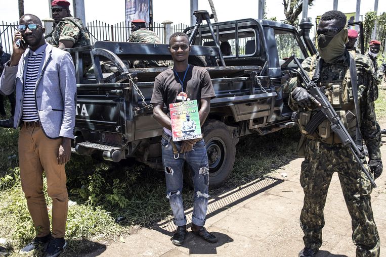 Een aanhanger van juntaleider kolonel Mamady Doumbouya staat met een portret van hem in het Volkspaleis in Conakry. Beeld AFP
