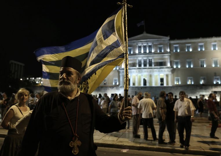 Een priester van de Griekse orthodoxe kerk bij een demonstratie tegen bezuinigingen voor het Griekse parlement. Beeld epa