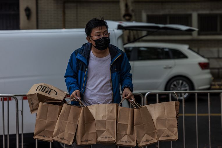 Pria pengantar jalan dengan makanan untuk penduduk Shanghai.  Tidak ada yang diizinkan keluar dari pintu.  foto ANP/EPA