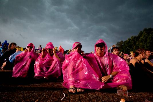Festivalbezoekers schuilen voor de regen.