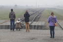 Leerlingen kijken uit over de rails bij vernietigingskamp Auschwitz.