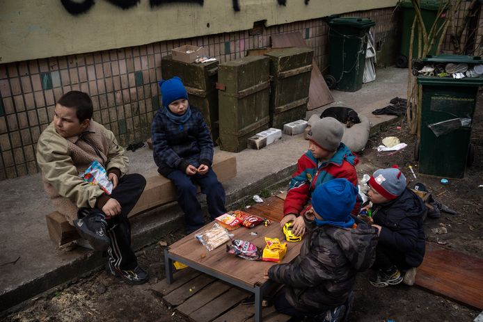 Kinderen zitten in Boetsja aan een klein tafeltje met wat snacks.