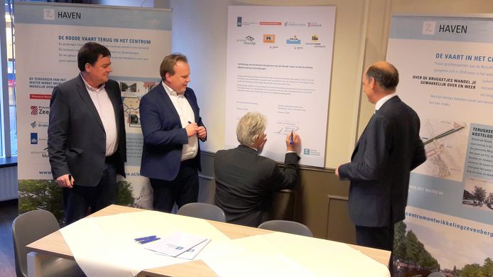 Aan de wand van het informatiecentrum op het haventracé hangt een uitvergroot contract. Links de wethouders, rechts de aannemers.