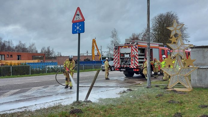 Brandweermannen maken de rijweg proper.