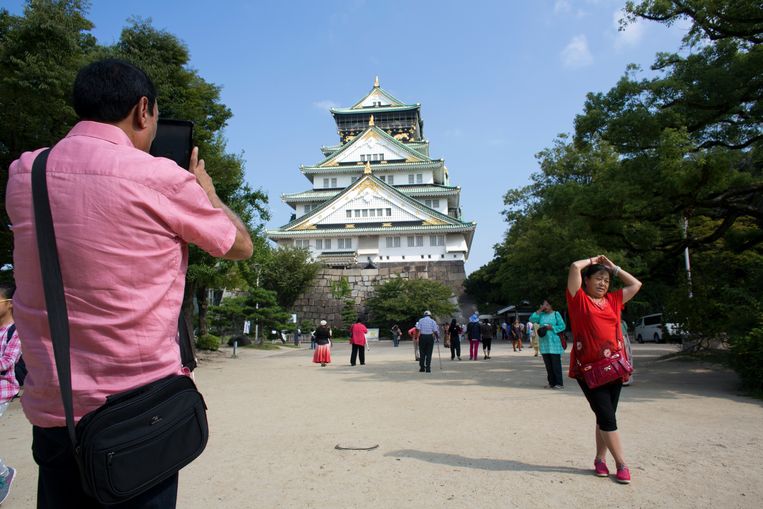 Een toerist zet een vrouw op de foto voor het kasteel in Osaka, een populaire attractie in de miljoenenstad.  Beeld Ton Koene