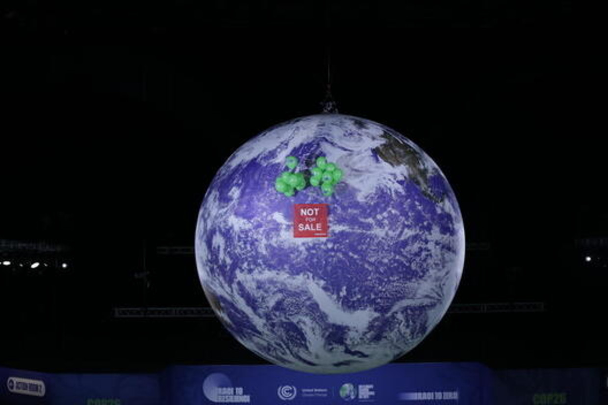Greenpeace liet vrijdagavond een spandoek op naast de gigantische wereldbol in het congrescentrum in Glasgow: Not fo sale. Beeld rv