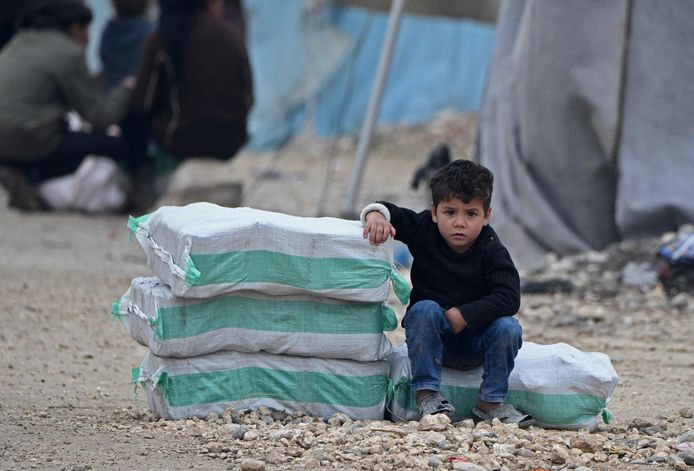 Een Syrisch jongetje zit naas hulpgoederen in een vluchtelingenkamp in het stadje Mehmediye aan de Syrisch-Turkse grens. Archiefbeeld.