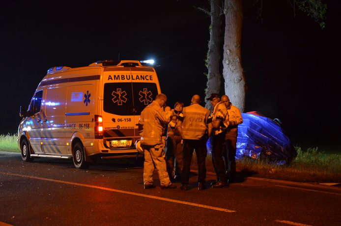 De hulpdiensten overleggen na het dodelijk ongeluk op de Nettelhorsterweg in Lochem. Het autowrak is ingepakt met een blauw zeil.