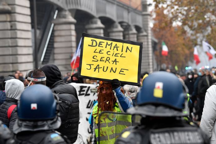 A demonstrator holds up a placard reading "tomorrow, the sky will be yellow" during a protest of Gilets Jaunes (yellow vest) in Paris on November 20, 2021. - Three candles on a placard "season 3" to celebrate the 3rd anniversary of the movement, several hundred "yellow vests" demonstrated in the afternoon in Paris, between Bercy and Alesia. (Photo by Alain JOCARD / AFP)