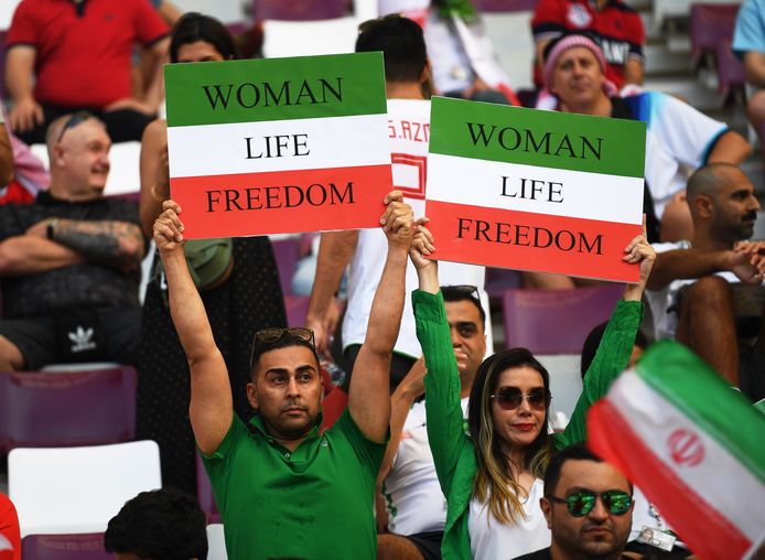 Fans houden bord omhoog waar "Vrouwen, leven, vrijheid" op te lezen staat.