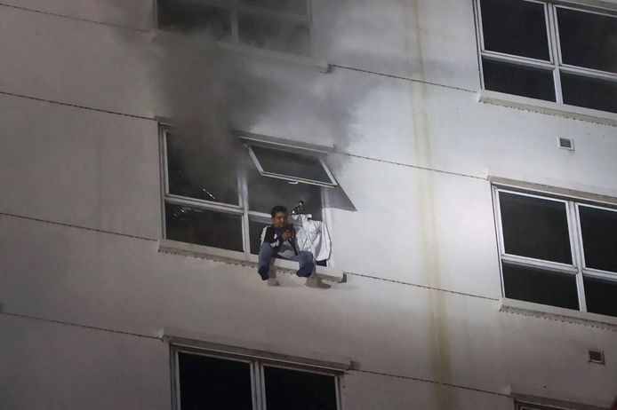 Een man zit in zijn raam terwijl de brand in het hotel-casino woedt.