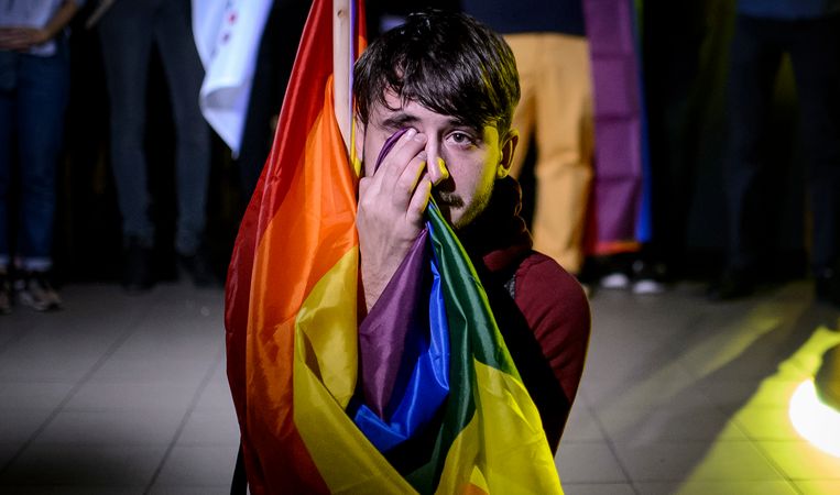 Een activist droogt zijn tranen met de regenboogvlag nadat de lage opkomstcijfers bekend zijn gemaakt.  Beeld AP