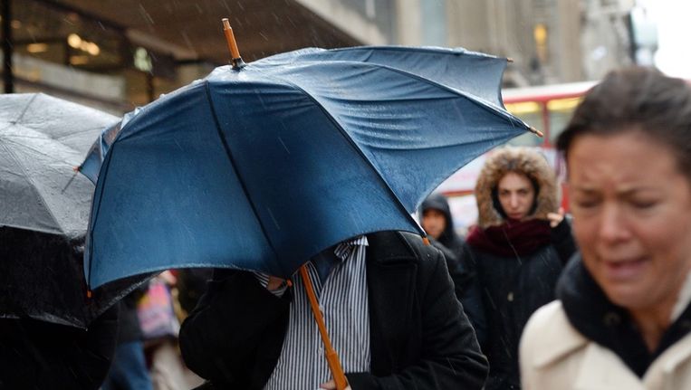 Een voetganger houdt zijn paraplu goed vast in London Beeld epa